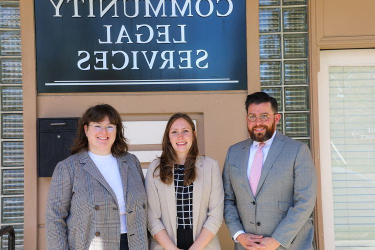 Three people pose for a photo outside of a building.